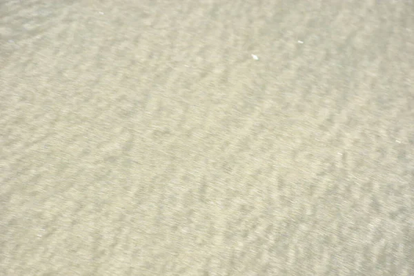 Rüzgâr ve sığ suların oluşturduğu doğal kum dalgalanmaları plaj yüzeyinde soyut desenler oluşturur. Tasarım ve doğa kavramları için ideal minimum kıyı arkaplanı, ince ışık ve organik kumlu detaylar.