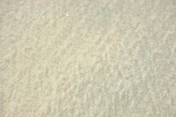 Rüzgâr ve sığ suların oluşturduğu doğal kum dalgalanmaları plaj yüzeyinde soyut desenler oluşturur. Tasarım ve doğa kavramları için ideal minimum kıyı arkaplanı, ince ışık ve organik kumlu detaylar.