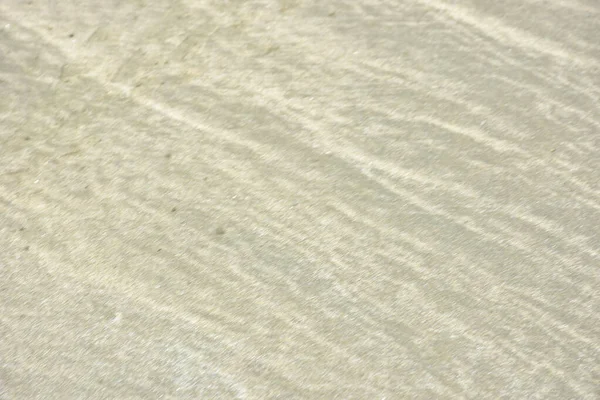 Rüzgâr ve sığ suların oluşturduğu doğal kum dalgalanmaları plaj yüzeyinde soyut desenler oluşturur. Tasarım ve doğa kavramları için ideal minimum kıyı arkaplanı, ince ışık ve organik kumlu detaylar.