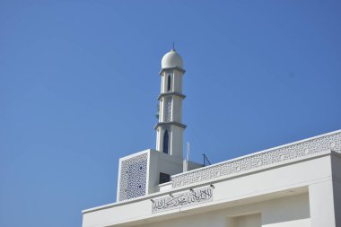 Zarif geometrik desenlere sahip modern beyaz cami minaresi açık mavi gökyüzüne karşı yükseliyor. Dini, kültürel ve barışçıl konsept betimlemeleri için ideal inanç, maneviyat ve Ramazan 'ı sembolize eden minimum İslami mimari.