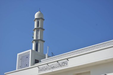 Zarif geometrik desenlere sahip modern beyaz cami minaresi açık mavi gökyüzüne karşı yükseliyor. Dini, kültürel ve barışçıl konsept betimlemeleri için ideal inanç, maneviyat ve Ramazan 'ı sembolize eden minimum İslami mimari.