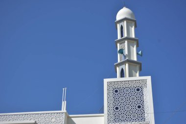 Zarif geometrik desenlere sahip modern beyaz cami minaresi açık mavi gökyüzüne karşı yükseliyor. Dini, kültürel ve barışçıl konsept betimlemeleri için ideal inanç, maneviyat ve Ramazan 'ı sembolize eden minimum İslami mimari.