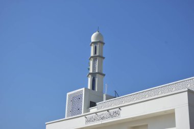 Zarif geometrik desenlere sahip modern beyaz cami minaresi açık mavi gökyüzüne karşı yükseliyor. Dini, kültürel ve barışçıl konsept betimlemeleri için ideal inanç, maneviyat ve Ramazan 'ı sembolize eden minimum İslami mimari.