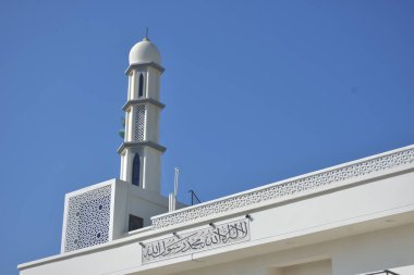 Zarif geometrik desenlere sahip modern beyaz cami minaresi açık mavi gökyüzüne karşı yükseliyor. Dini, kültürel ve barışçıl konsept betimlemeleri için ideal inanç, maneviyat ve Ramazan 'ı sembolize eden minimum İslami mimari.