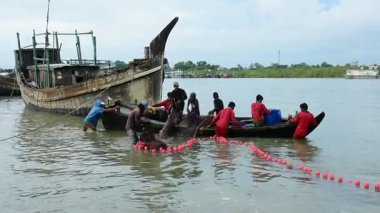 Bir grup balıkçı, Bangladeş 'in Coxs Bazar semtindeki Bakkhali Nehri' nde büyük bir barikat kuruyor. Sular yükseldiğinde geleneksel nehir balıkçılığı faaliyetleri, kırsal geçim kaynaklarını ve Güney Asya kıyı bölgesinde küçük ölçekli balıkçılık uygulamalarını gösteriyor.