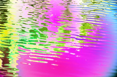 bir su yüzeyinde gökkuşağı renkleri yansıması