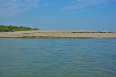 Bakkhali Nehri 'nin Cox' s Bazar yakınlarında Bengal Körfezi 'yle buluştuğu sakin sahil manzarası, kumlu kıyı şeridi, sakin su ve açık kıyı ufkunun yer aldığı Bangladeş' te gün ışığı altında