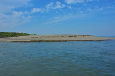 Bakkhali Nehri 'nin Cox' s Bazar yakınlarında Bengal Körfezi 'yle buluştuğu sakin sahil manzarası, kumlu kıyı şeridi, sakin su ve açık kıyı ufkunun yer aldığı Bangladeş' te gün ışığı altında