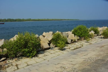 Bangladeş kıyısındaki Maheshkhali Kanalı boyunca kaya seti gelgit sularını, kıyı şeridini ve sakin bir tropikal estuarin ortamında kıyı mühendisliğini gösteriyor..