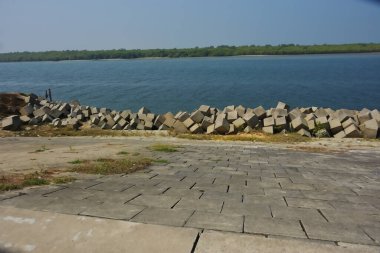 Cox 's Bazar, Bangladeş' teki gelgit suyu ve kaya setinin yanında beton kıyı yolu kıyı şeridi koruması, kıyı altyapısı ve tropikal estuarin manzarasını gösteriyor..