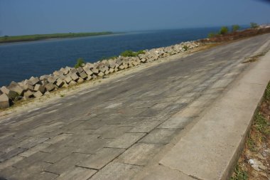Cox 's Bazar, Bangladeş' teki gelgit suyu ve kaya setinin yanında beton kıyı yolu kıyı şeridi koruması, kıyı altyapısı ve tropikal estuarin manzarasını gösteriyor..