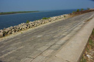 Cox 's Bazar, Bangladeş' teki gelgit suyu ve kaya setinin yanında beton kıyı yolu kıyı şeridi koruması, kıyı altyapısı ve tropikal estuarin manzarasını gösteriyor..