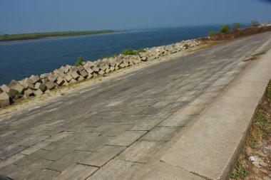 Cox 's Bazar, Bangladeş' teki gelgit suyu ve kaya setinin yanında beton kıyı yolu kıyı şeridi koruması, kıyı altyapısı ve tropikal estuarin manzarasını gösteriyor..