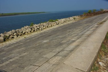 Cox 's Bazar, Bangladeş' teki gelgit suyu ve kaya setinin yanında beton kıyı yolu kıyı şeridi koruması, kıyı altyapısı ve tropikal estuarin manzarasını gösteriyor..