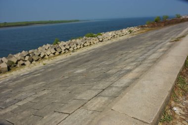 Cox 's Bazar, Bangladeş' teki gelgit suyu ve kaya setinin yanında beton kıyı yolu kıyı şeridi koruması, kıyı altyapısı ve tropikal estuarin manzarasını gösteriyor..