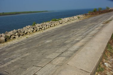 Cox 's Bazar, Bangladeş' teki gelgit suyu ve kaya setinin yanında beton kıyı yolu kıyı şeridi koruması, kıyı altyapısı ve tropikal estuarin manzarasını gösteriyor..