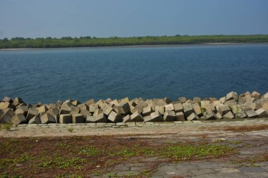 Cox 's Bazar, Bangladeş' teki Maheshkhali Kanalı boyunca yer alan beton blok seti ve kıyı şeridi erozyon kontrolü ve deniz altyapısı için ağır görev taşları ve çimento yapıları yer alıyor..