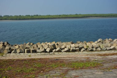 Cox 's Bazar, Bangladeş' teki Maheshkhali Kanalı boyunca yer alan beton blok seti ve kıyı şeridi erozyon kontrolü ve deniz altyapısı için ağır görev taşları ve çimento yapıları yer alıyor..