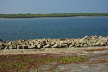 Cox 's Bazar, Bangladeş' teki Maheshkhali Kanalı boyunca yer alan beton blok seti ve kıyı şeridi erozyon kontrolü ve deniz altyapısı için ağır görev taşları ve çimento yapıları yer alıyor..