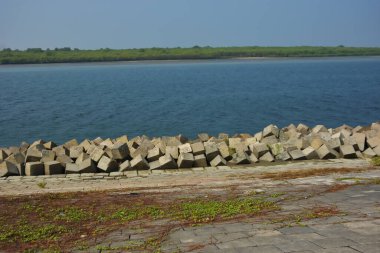 Cox 's Bazar, Bangladeş' teki Maheshkhali Kanalı boyunca yer alan beton blok seti ve kıyı şeridi erozyon kontrolü ve deniz altyapısı için ağır görev taşları ve çimento yapıları yer alıyor..