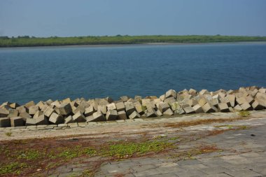 Cox 's Bazar, Bangladeş' teki Maheshkhali Kanalı boyunca yer alan beton blok seti ve kıyı şeridi erozyon kontrolü ve deniz altyapısı için ağır görev taşları ve çimento yapıları yer alıyor..