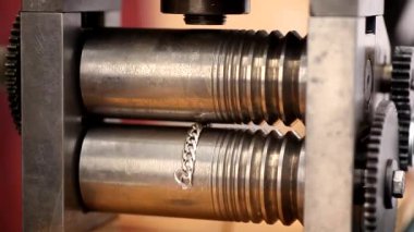 Kuyumcu, kuyumcu atölyesinde demir işleme makinesiyle gümüş zincir işliyor..