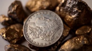 Amerikan gümüşü bir dolar ve altın külçeler beyaz arka planda dönüyor..