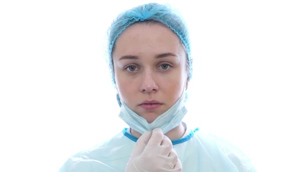 Женщина-врач во время пандемии коронавируса ковид-19 надевает очки и защитную маску, красные пятна. Близкий портрет уставшего врача — стоковое видео