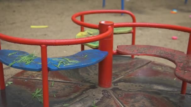 Solitario balanceo abandonado vacío rojo en un viejo parque de atracciones abandonado. Asiento oscilante moviéndose hacia adelante y hacia atrás. El carrusel se mueve lentamente. Concepto de soledad o secuestro de niños. Zona peligrosa.Ciudad fantasma. — Vídeo de stock