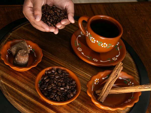 Kahve çekirdekleri ve baharatlar kil bardağa dökülüyor.