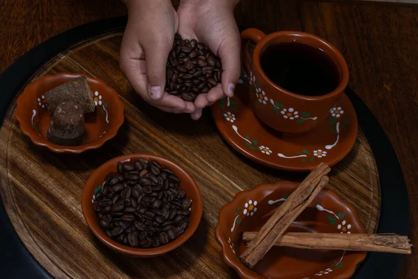 Kahve çekirdekleri ve baharatlar kil bardağa dökülüyor.