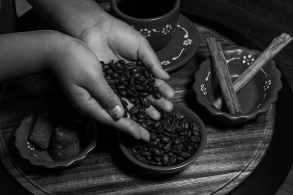 Kahve çekirdekleri ve baharatlar kil bardağa dökülüyor.