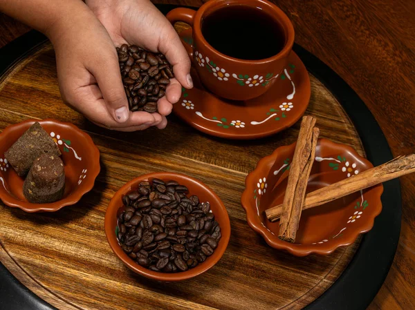 Kahve çekirdekleri ve baharatlar kil bardağa dökülüyor.