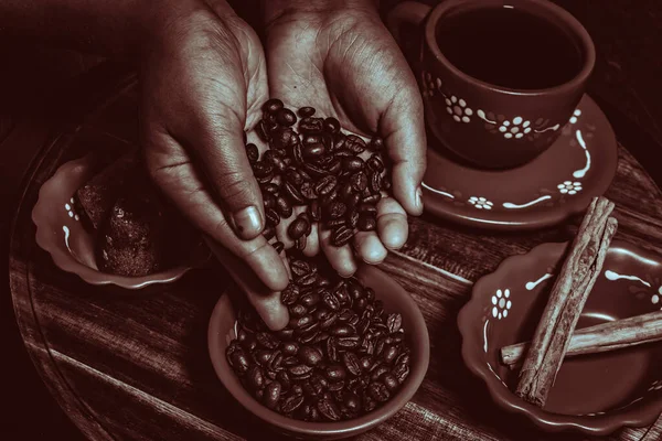 Kahve çekirdekleri ve baharatlar kil bardağa dökülüyor.