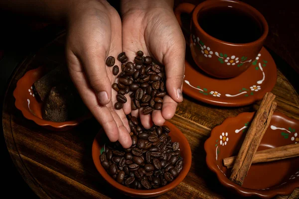 Kahve çekirdekleri ve baharatlar kil bardağa dökülüyor.