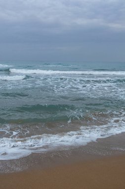 Akdeniz kıyısındaki kahverengi kumsalda kış sabahı ve Kuzey Kıbrıs 'ta gökyüzünde bulutlar