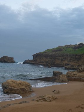 Akdeniz 'de bulutlu bir sabah. Kuzey Kıbrıs Rum Kesimi' nin Kyrenia kentinde kumsalda taş ve kayalıklarla dalgalar var.