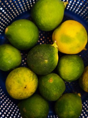 Tahta bir masada taze yeşil ve sarı limonlar.