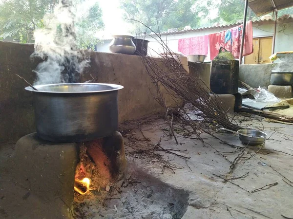 Traditional way of making food on open fire in old kitchen in a village, Rajasthan India. Pots and pans on the stove over a natural fire for cooking. Rural kitchen using bio wood fuel for cooking