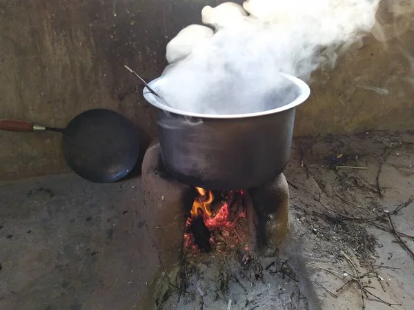 Traditional way of making food on open fire in old kitchen in a village, Rajasthan India. Pots and pans on the stove over a natural fire for cooking. Rural kitchen using bio wood fuel for cooking