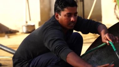 Ocak 2021 - Mahroli, Jaipur, Hindistan. Sabah vakti, Hintliler demir tavayı temizliyor. Demir Pan gemilerin büyüklüğü çoğunlukla ziyafet amacıyla kullanılır..