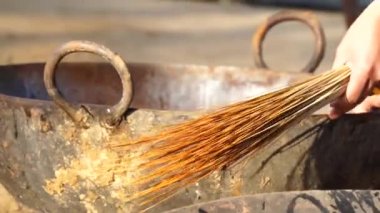 Ocak 2021 Mahroli, Jaipur, Hindistan. Büyük demir kazanı su ve süpürgeyle temizleyen genç bir Hintli. Şölen için sebze kızartmak için kazan temizleyen adam..