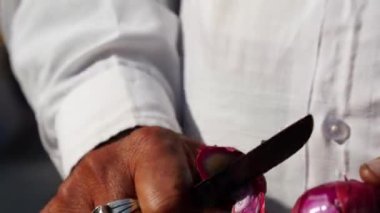 Büyük paslanmaz çelik bıçakla soğan kabuğunun dışını soyarken çekilmiş bir fotoğraf. Mutfak konsepti.