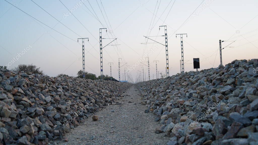 Pedestrian way in the Railway track disappearing in the horizon in the desert. Indian rail pathway through electricity wire.