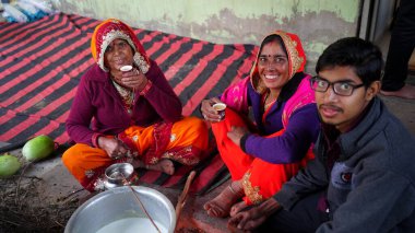 30 Aralık 2020 Khatoo, Jaipur, Hindistan. Şeffaf gözlükleriyle kameraya bakan sevimli küçük bir çocuk ve gülen yüzlü çay içen diğer aile fertleri. Kırsal yaşam tarzı kavramı.