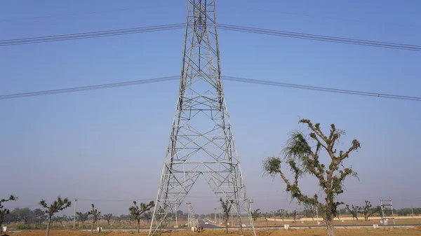 10 February 2021- Sikar, Jaipur, India. Triangular shape iron power supply posts with blue sky nature background. Electricity transmission tower and supply lines closeup.