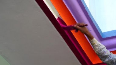 Ressam duvarda renk yapar. Profesyonel Hintli ressam boya fırçasıyla duvar dokusuna el boyası çizer..