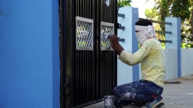 Metal kapıya boyanmış bir sanatçı görüntüsü. Boya kutusuna odaklan. Odaklanmış adam gümüş rengiyle resim yapmakla meşgul..