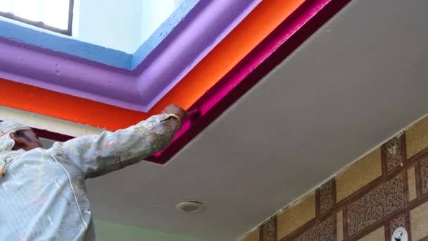 Ervaren schilder kleurt plint, bevestiging tussen plafond en muren met verschillende kleuren. Handenarbeid in een moderne reparatie van appartementen. — Stockvideo