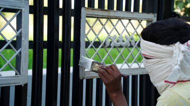 Kapıda boya renkleri var. Erkek ressam Enter Gate 'de çalışıyor. Profesyonel bir işçinin güvenlik kapısında gümüş rengi var..